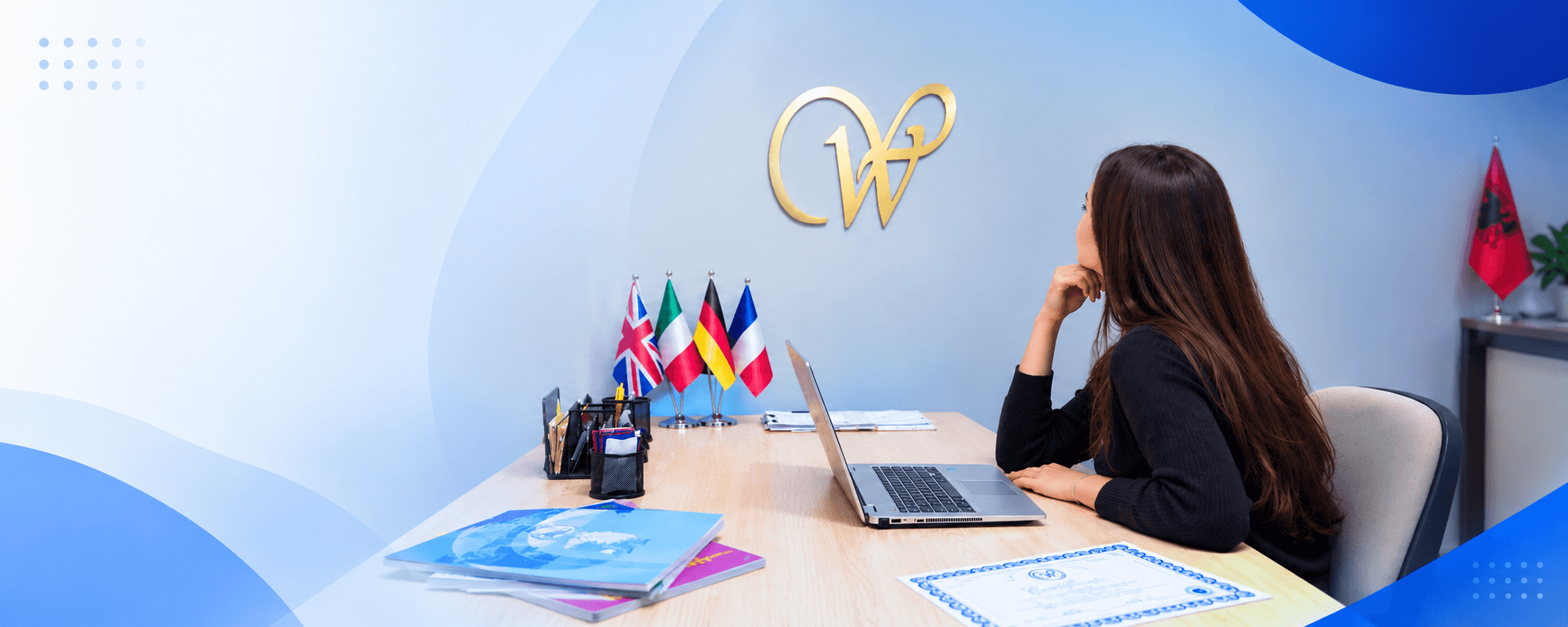 Stafi i New Wisdom Center në zyrat e qendrës, me flamujt e gjuhëve të huaja anglisht, italisht, gjermanisht dhe frëngjisht — kurse gjuhësh dhe programimi në Elbasan e Tiranë